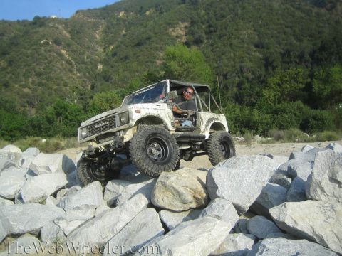 1987 Suzuki Samurai - A white 1987 Suzuki Samurai navigates a rocky terrain with a driver behind the wheel.