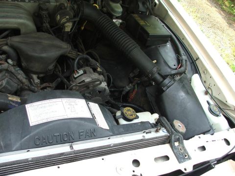 1991 Ford LTD Crown Victoria - Engine bay components including air intake, fan shroud with caution label, and coolant reservoir.