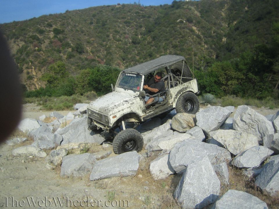 1987 Suzuki Samurai off-roading over large rocks on a hillside