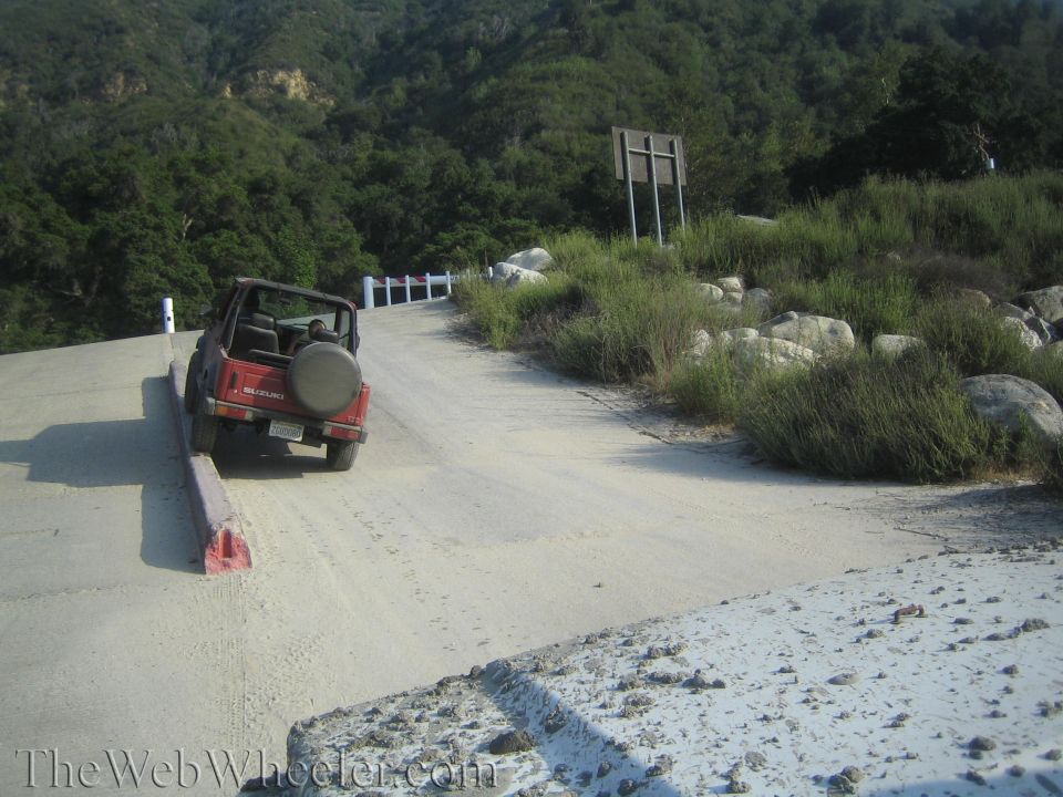 1987 Suzuki Samurai parked on the side of a dirt road, facing uphill