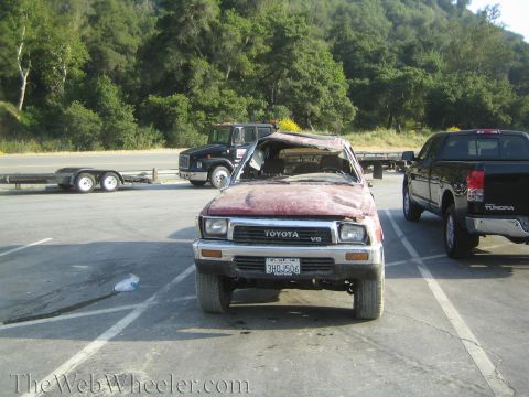 1987 Suzuki Samurai - A damaged red Toyota pickup truck sits in a parking lot next to a black Toyota Tundra.