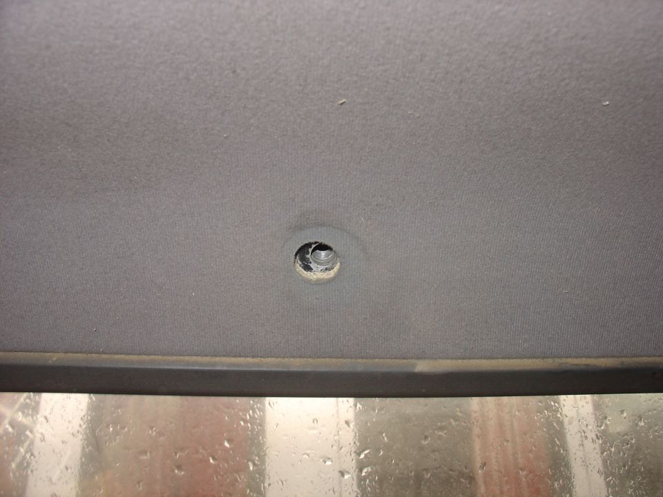Close-up of a gray vehicle headliner with a circular hole drilled into it