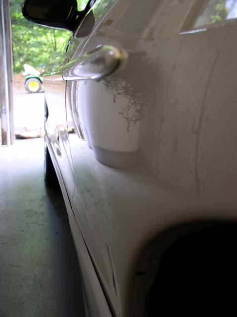 1996 Ford Probe - The side of a white car shows damage to its clear coat, with a lawnmower visible in the background.