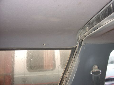 1988 Ford Bronco - Interior view of a vehicle's headliner and window frame, showing signs of wear and dust.