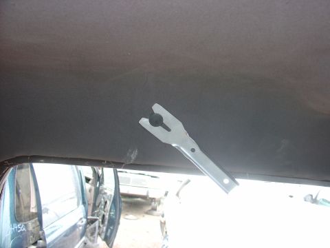1988 Ford Bronco - View of a vehicle's interior headliner, showing a metal clip and the exterior of another vehicle through the window.