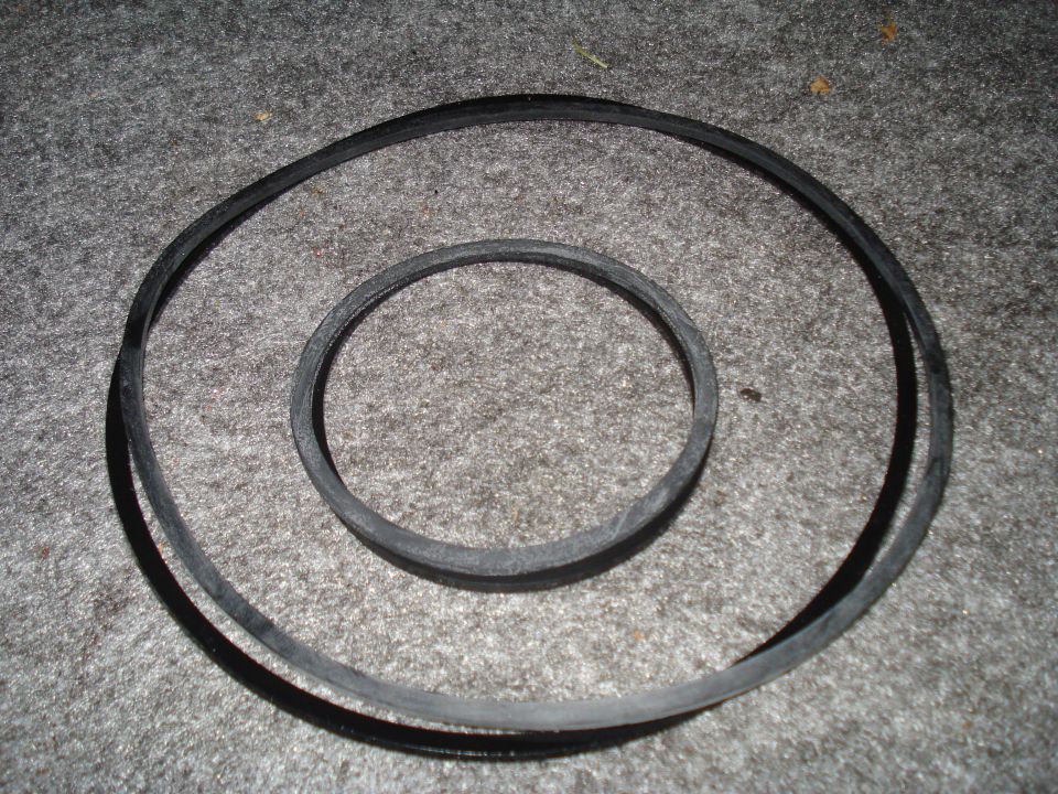 Two rubber belts, one larger than the other, lying on a grey carpeted surface