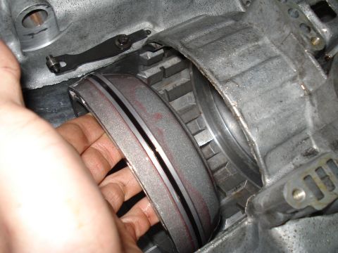 1984 Ford Bronco - Close-up of a transmission band being held, showing wear and red markings within the internal components.