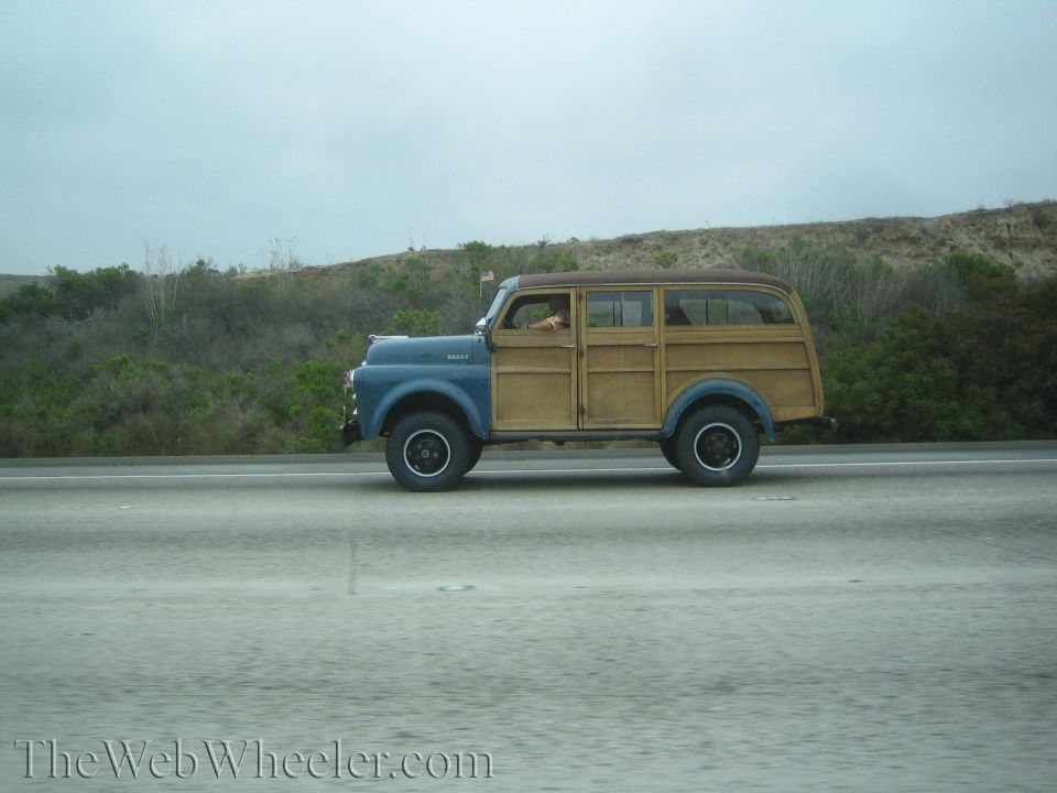 Blue and wood-bodied vintage panel woodie wagon on a highway