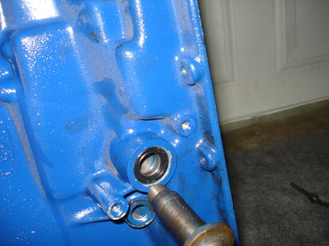 1984 Ford Bronco - Close-up of a blue engine component, possibly a transmission housing, with a shaft and bearing visible.