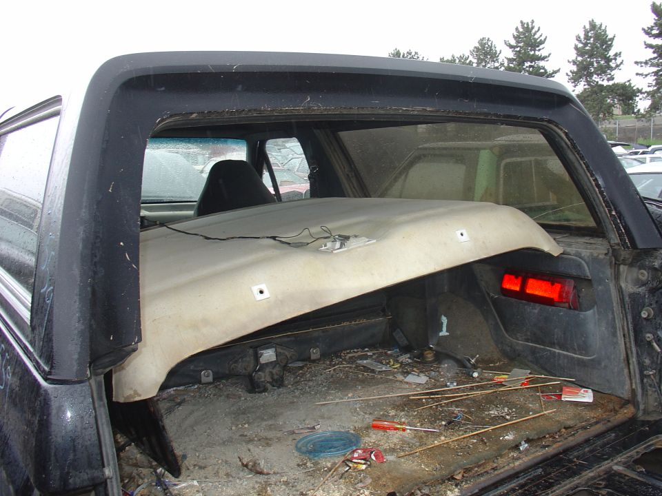 Vehicle interior with detached headliner, debris on floor, and visible taillight