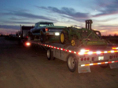 1994 Ford F-150 - A 1979 Ford F-150 and John Deere tractor are transported on a flatbed trailer at dusk.