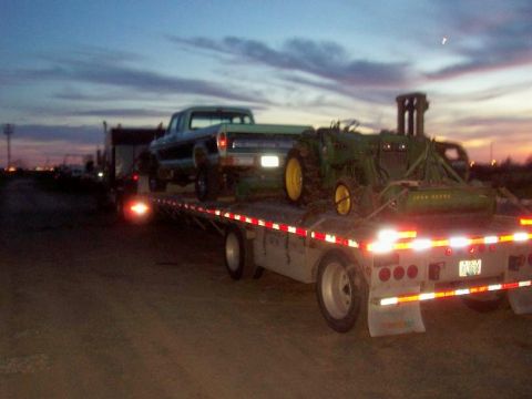 1994 Ford F-150 - A 1970s Ford pickup truck is loaded onto a flatbed trailer with a John Deere tractor.