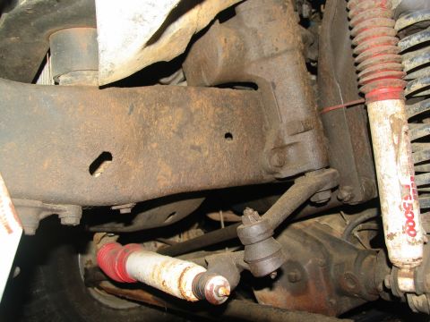 1978 Ford Bronco - Close-up view of the heavily rusted undercarriage of a vehicle, revealing suspension parts and a differential.