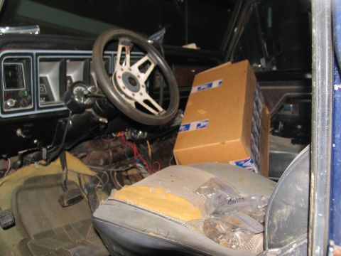 1978 Ford Bronco - The interior of a 1978 Ford Bronco shows a cardboard box and bags of parts on the passenger seat, with the dashboard and steering wheel vis…