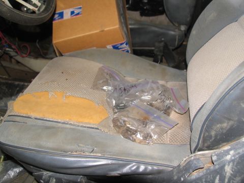 1978 Ford Bronco - Small plastic bags containing parts are placed on the worn seats of a vehicle, with a cardboard box in the background.