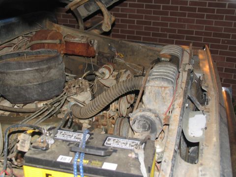 1978 Ford Bronco - The engine bay shows significant rust and wear, with visible hoses and a battery.