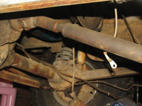1978 Ford Bronco - The heavily rusted undercarriage of a vehicle, with visible suspension and drivetrain parts.