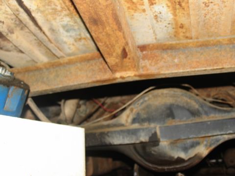 1978 Ford Bronco - The underside of a vehicle shows significant rust on the frame and rear axle components.