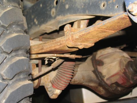 1978 Ford Bronco - The underside of a vehicle shows significant rust on the leaf springs and axle components.