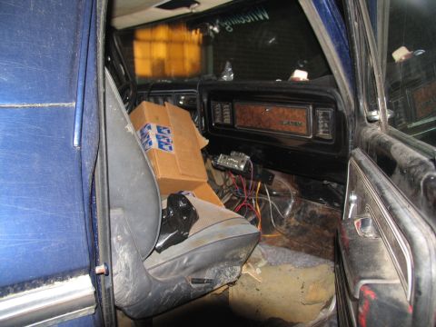 1978 Ford Bronco - The interior of a vehicle shows a passenger seat with a box and trash, and a dashboard with exposed wiring.