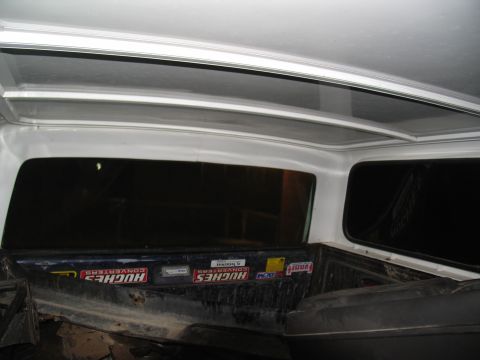 1978 Ford Bronco - The interior of a truck bed shows several stickers on the cab wall behind the rear window.