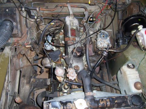 1974 Land Rover Land Rover - The engine bay shows a complex arrangement of hoses, wires, and engine components, some showing signs of age and wear.