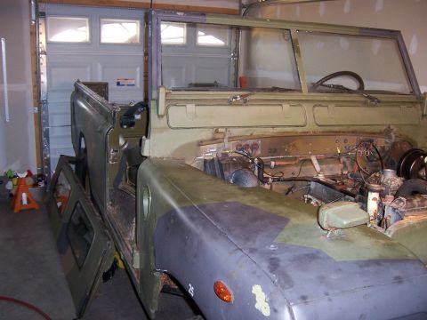 1974 Land Rover Land Rover - Olive green Land Rover Series III in a garage, undergoing restoration with its hood open and doors removed.