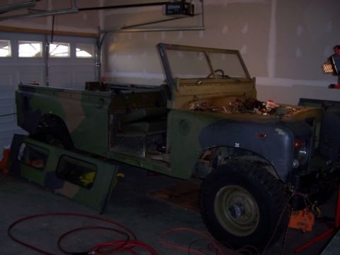 1974 Land Rover Land Rover - Land Rover in garage, doors off, undergoing restoration work. Camouflage paint is visible.