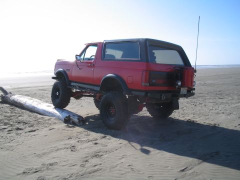 1989 Ford Bronco - This lifted 1989 Ford Bronco is parked on the sand near the ocean, with a spare fuel can mounted on the rear.