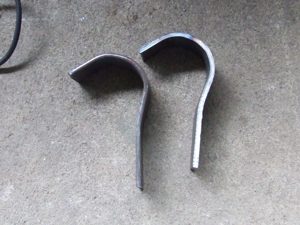 Two bent metal pieces on concrete floor