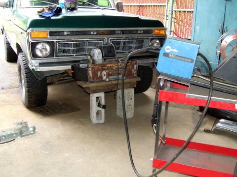 1979 Ford Bronco - A green 1979 Ford Bronco's front end is visible, with a winch assembly supported by cinder blocks.