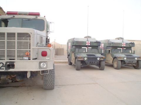 1981 Ford Bronco - A large military truck is parked next to two Humvees that appear to be configured as medical transport vehicles.