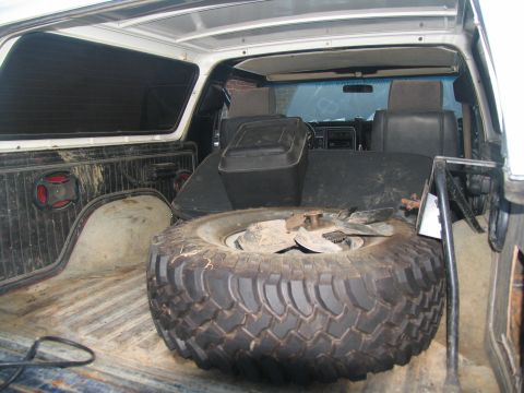 1978 Ford Bronco - The interior of a vehicle is shown, with a large spare tire taking up most of the cargo area.