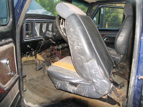 1978 Ford Bronco - The interior of a 1978 Ford Bronco reveals worn seats, exposed wiring, and a dated dashboard.