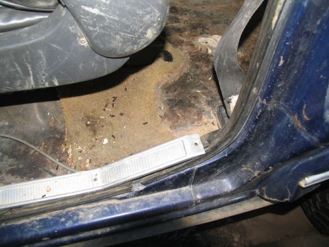 1978 Ford Bronco - The interior of a blue vehicle shows a dirty floor with debris and a seatbelt.