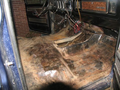 1978 Ford Bronco - The floor of this vehicle's interior shows significant rust and exposed wiring, indicating it's undergoing restoration or repair.