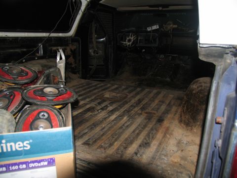 1978 Ford Bronco - The interior of a 1978 Ford Bronco shows a worn dashboard and a box of speakers in the cargo area.
