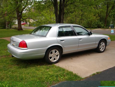 2003 Ford Crown Victoria - A silver 2003 Ford Crown Victoria is parked on a driveway with a grassy lawn beside it.
