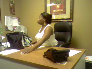 1989 Ford Bronco - A woman is seated at her desk in an office environment, with a fan and artwork visible in the background.