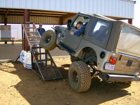 2004 Jeep Wrangler - A Jeep Wrangler is shown ascending a metal ramp, with a driver at the wheel and another person observing.