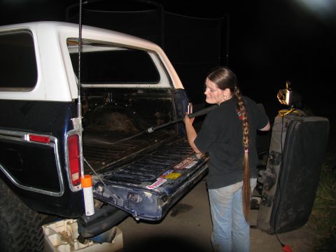 1978 Ford Bronco - A woman pressure washes the interior of a 1978 Ford Bronco's tailgate area at night.