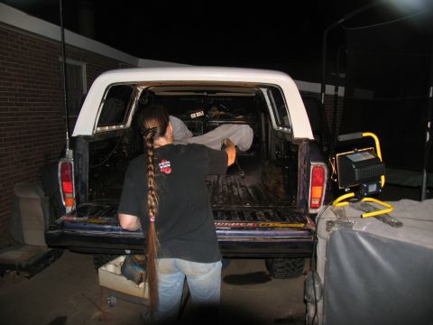 1978 Ford Bronco - Person cleaning out the bed of a 1978 Ford Bronco with a white camper shell at night.