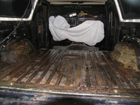 1978 Ford Bronco - The interior of a truck bed is shown, with a white tarp obscuring an object within.