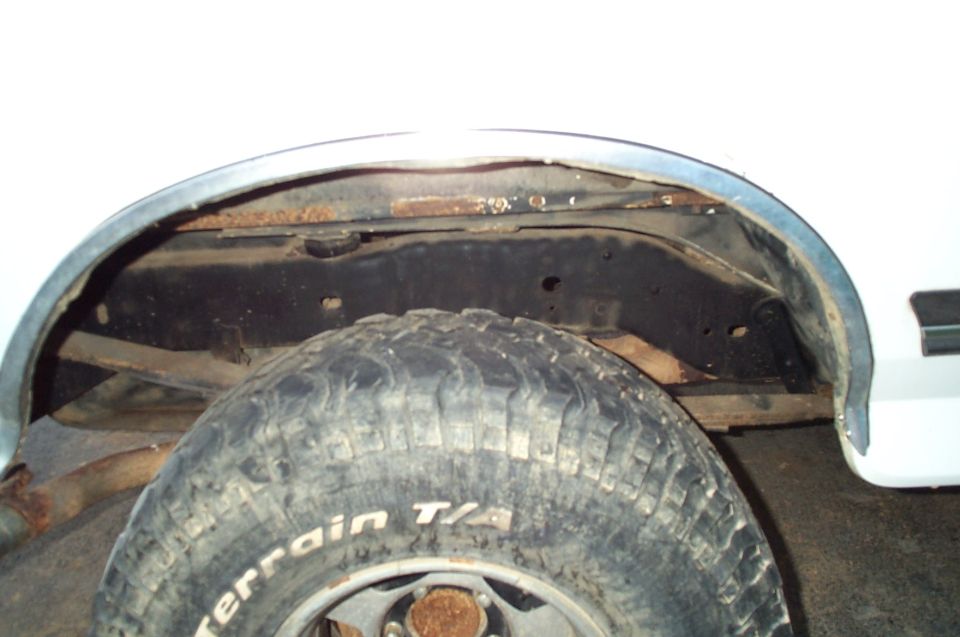 Rear wheel well of a white truck with BFGoodrich Mud-Terrain T/A tire and rusted inner fender