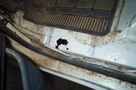 1988 Ford Bronco - Interior floor pan shows significant rust damage and a hole.