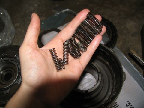1978 Ford Bronco - Transmission springs are held in a hand, with disassembled transmission components visible in the background.