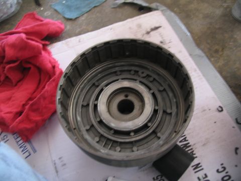 1978 Ford Bronco - A disassembled transmission clutch drum sits on a cardboard surface, with shop rags to the left.