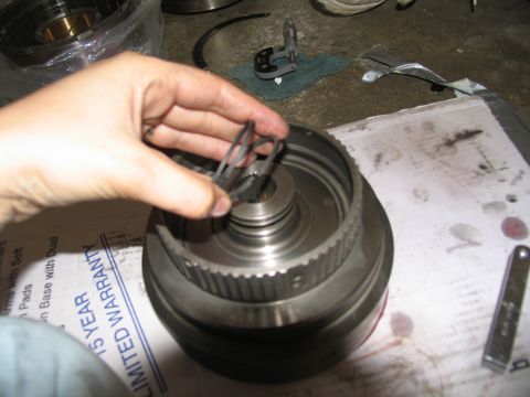 1978 Ford Bronco - Assembling transmission components, hand holds snap rings over a part.
