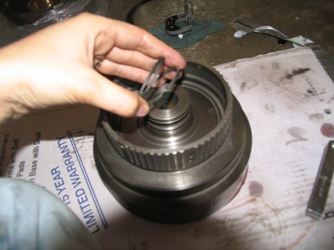 1978 Ford Bronco - A hand holds small metal rings over a disassembled transmission part, with a 'Limited Warranty' box visible.