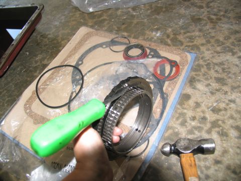 1978 Ford Bronco - A collection of transmission rebuild parts, including gaskets and seals, are laid out on a concrete surface with tools.